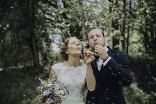 Brautpaar bläst Seifenblasen nach der freien Trauung im Wald