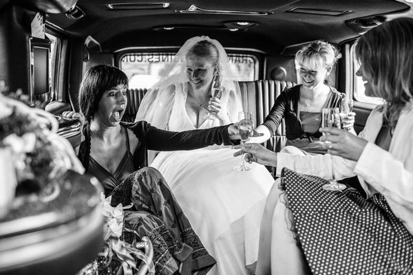 Braut und Brautgesellschaft auf dem Weg zur Hochzeit in einer Limousine | Strauß & Fliege