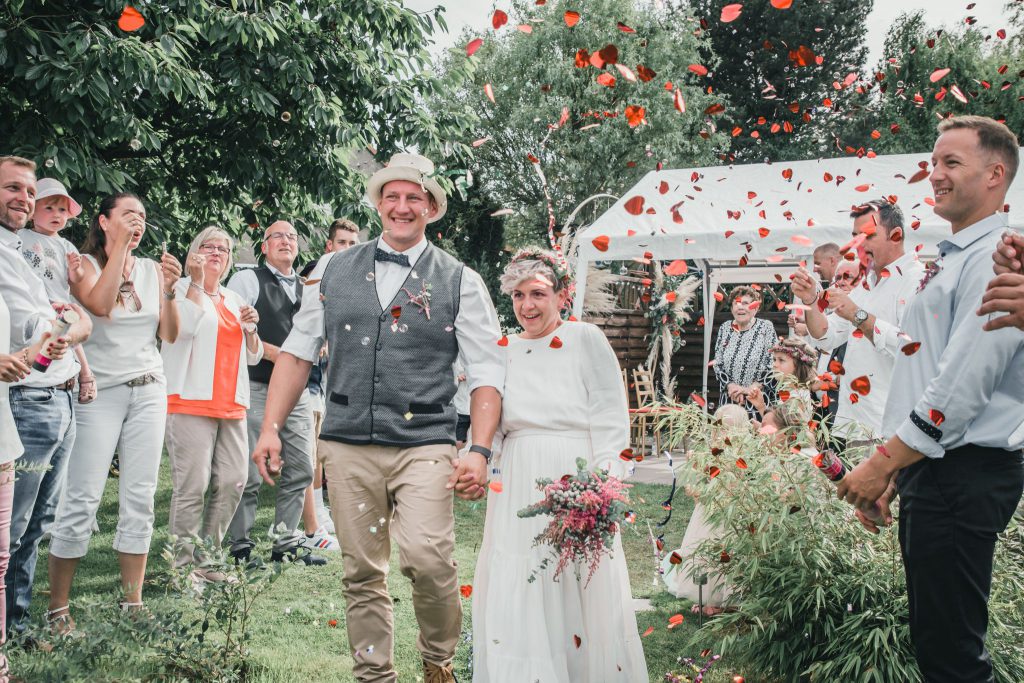 Blumenregen auf das Brautpaar beim Auszug aus der Trauung im Garten | Strauß & Fliege