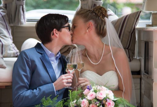 Braut und Braut küssen sich nach der queeren Hochzeit