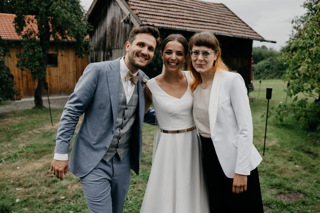 Strahlendes Brautpaar mit Traurednerin von Strauß & Fliege