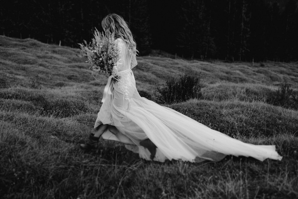 Strahlende Boho Braut bei der Hochzeit auf einer Almwiese | Strauß & Fliege