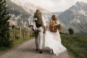 Brautpaar mit Wanderrucksäcken beim Spaziergang in den Bergen