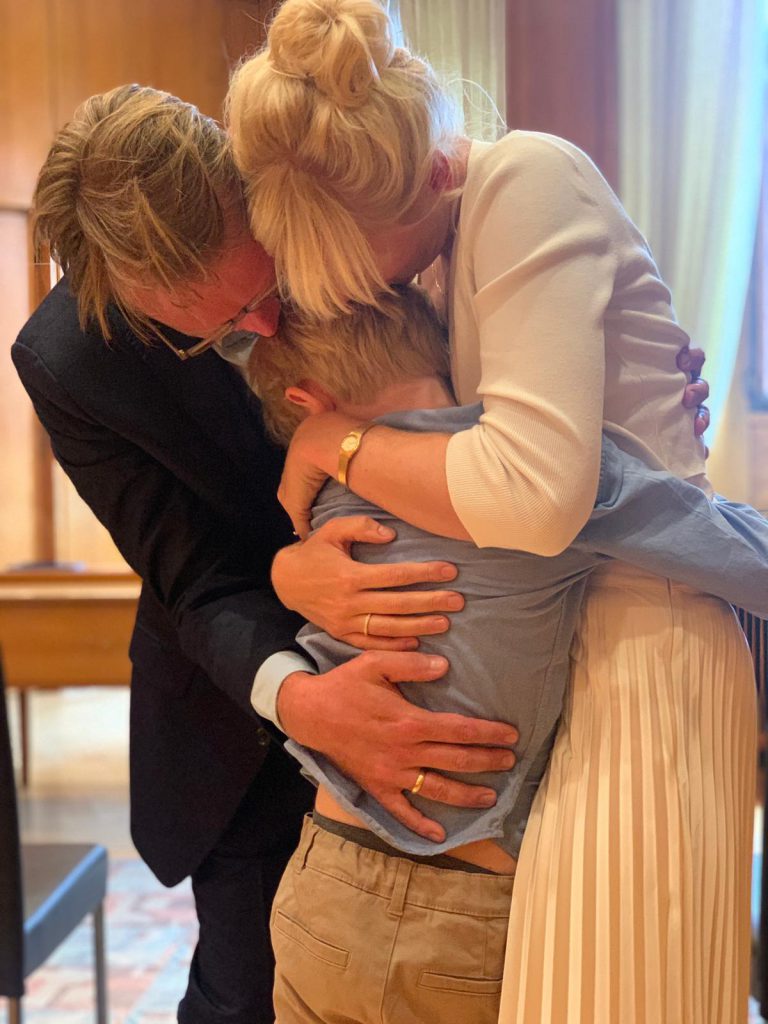 Glückliches Paar umarmt kleinen Sohn nach dem Ja-Wort auf dem Standesamt