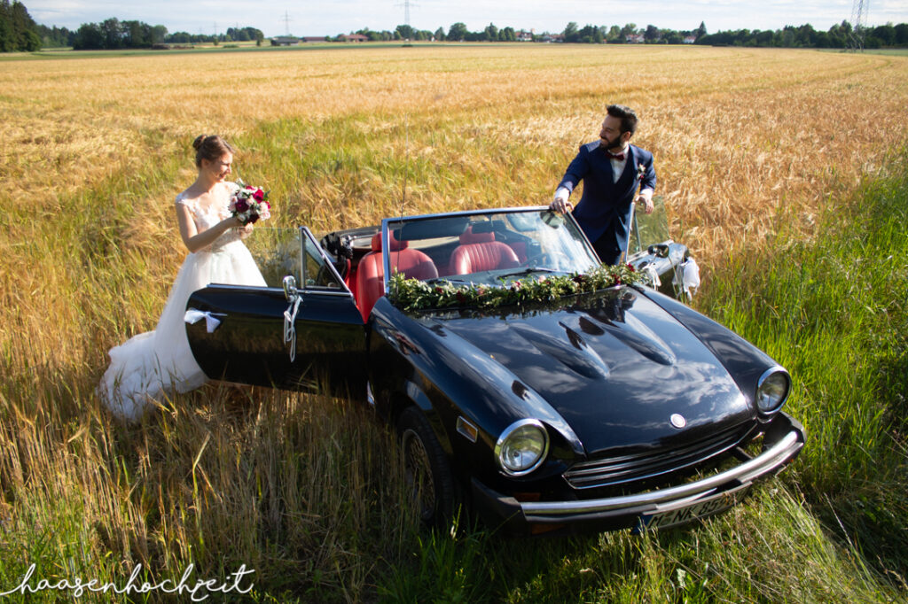 Oldtimer Cabrio als Brautauto in einer Sommerwiese | Strauß & Fliege