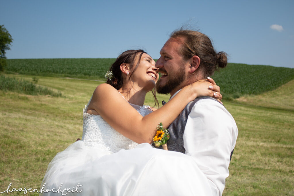 Lachendes Brautpaar im freien Feld | Strauß & Fliege