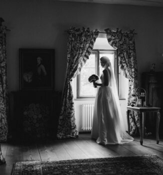 Braut steht erwartungsvoll am Fenster