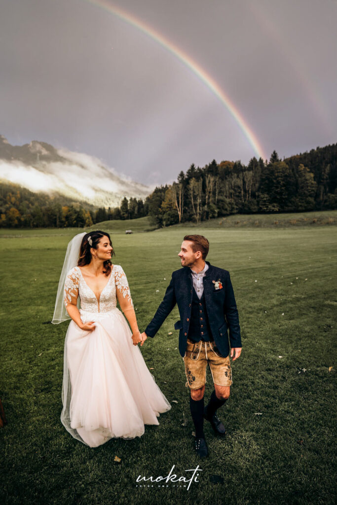 Freie Trauung auf der Alm | Brautpaar unter Regenbogen | Strauß & Fliege