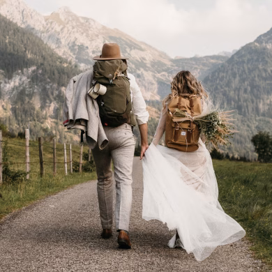 Brautpaar mit Wanderrucksäcken beim Spaziergang in den Bergen